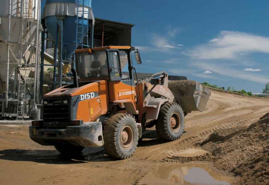 Погрузчик добавляет щебень в бункер завода
